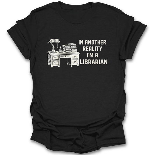 Brown t-shirt with a graphic of a desk and books, and text 'In another reality I'm a librarian' on a white background. funny book reading literary t shirt