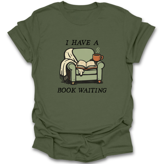 Green t-shirt with a graphic of a chair, book, and cup with text 'I HAVE A BOOK WAITING' on a white background. funny book reading literary t shirt