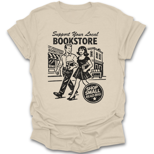 Beige t-shirt with a graphic of a man and woman walking past a bookstore and text 'Support Your Local Bookstore'. funny book reading literary t shirt