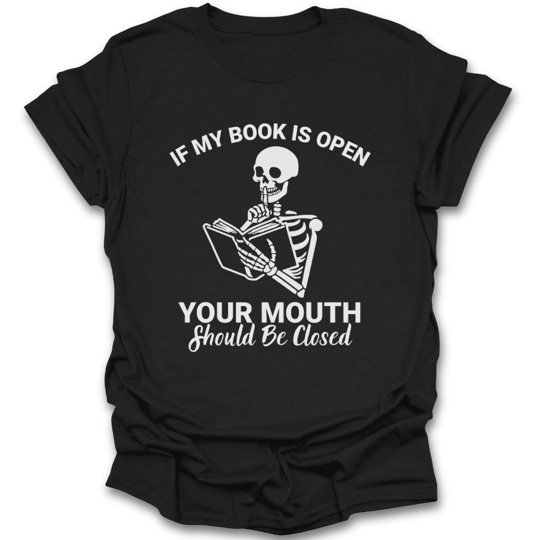 Black t-shirt with a skeleton reading a book graphic and text on a white background funny book reading literary t shirt