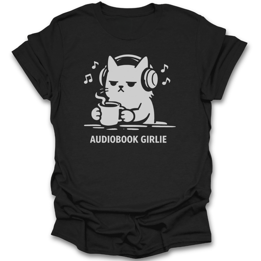 Black t-shirt with a graphic of a cat wearing headphones and holding a mug, with 'Audiobook Girlie' text. reading audio book t shirt