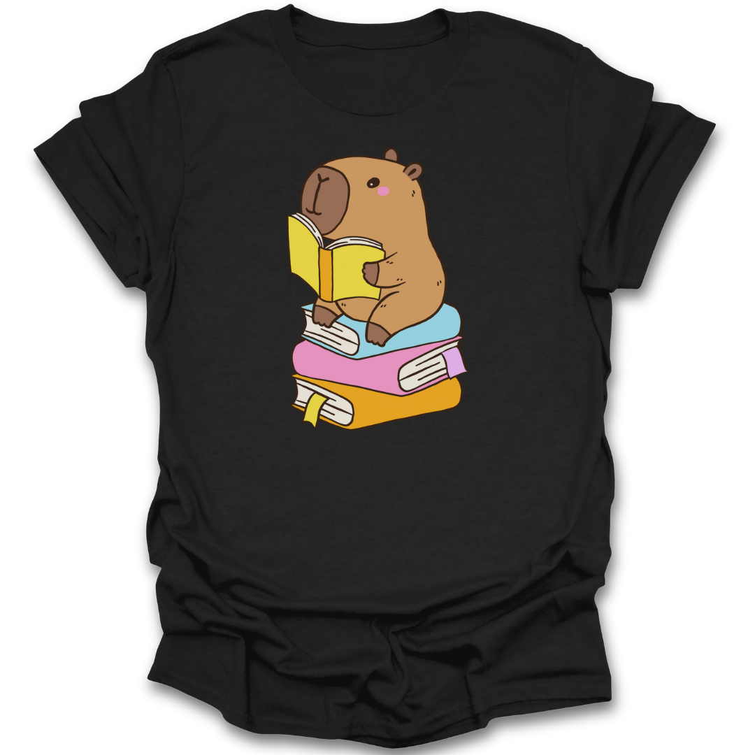 Black t-shirt with a cartoon capybara reading a book design on a white background 