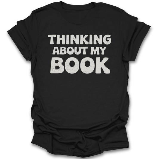 Black t-shirt with 'THINKING ABOUT MY BOOK' text on a white background funny book reading literary t shirt