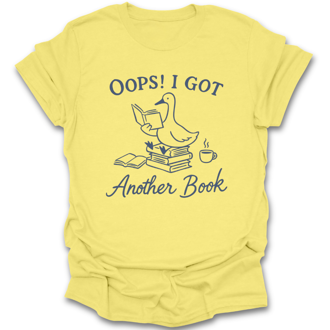 Yellow t-shirt with a graphic of a duck and text 'Oops! I got another book' on a white background. oops i got another book shirt, funny book lover shirt, bookish t-shirt, reader gift, bookworm apparel, bookstore shirt, bibliophile tee, reading humor shirt, book club gift, coffee and books shirt