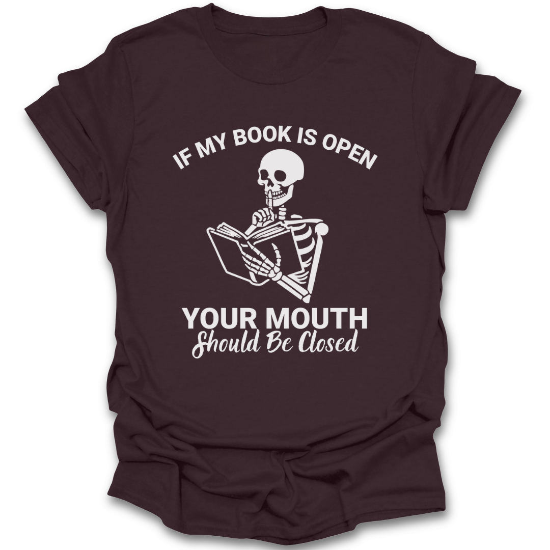 Brown t-shirt with a skeleton reading a book graphic and text on a white background funny book reading literary t shirt