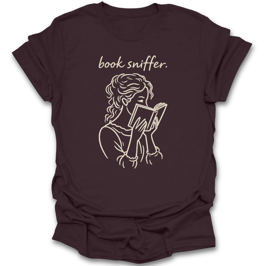 Brown t-shirt with a graphic of a person reading a book and the text 'book sniffer' on a white background. funny book reading literary t shirt