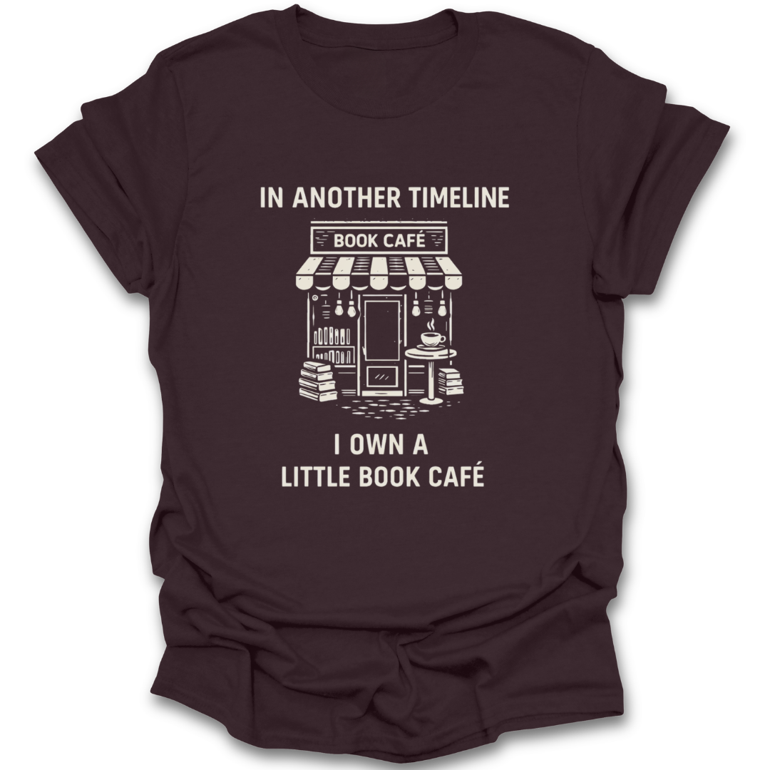 Brown t-shirt with white graphic and text 'In Another Timeline Book Café I Own a Little Book Café' on a white background funny book reading literary t shirt