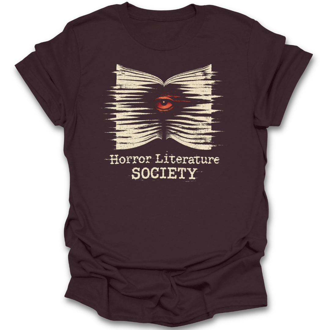 Brown t-shirt with 'Horror Literature Society' design featuring an eye in a book on a white background. horror literature shirt, horror book shirt, book lover shirt, horror reader gift, gothic book shirt, dark academia shirt, spooky bookish shirt, literature society tee, horror books apparel, bookworm shirt.&nbsp;