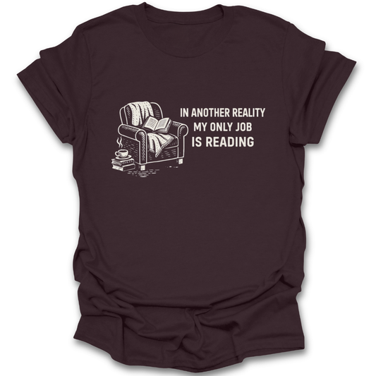 Brown t-shirt with a graphic of a couch, books, and a cup, and text 'In another reality my only job is reading' on a white background. funny book reading literary t shirt