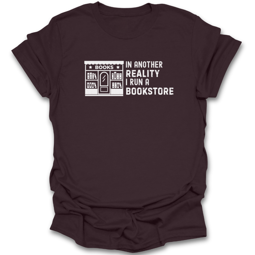 Brown t-shirt with white graphic and text 'In another reality I run a bookstore' on a white background reading t shirt