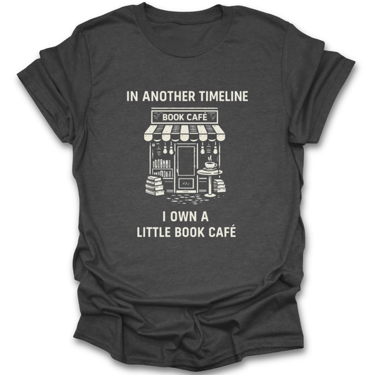 Black t-shirt with white graphic and text 'In another timeline I own a little book café' on a white background funny book reading literary t shirt