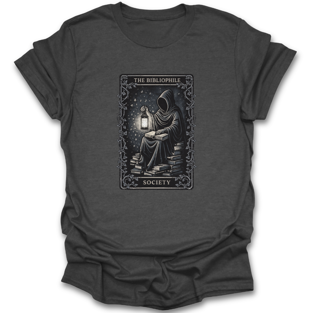 Dark gray t-shirt with a graphic of a person reading a book by lantern light, surrounded by books, on a white background.  book reading literary t shirt