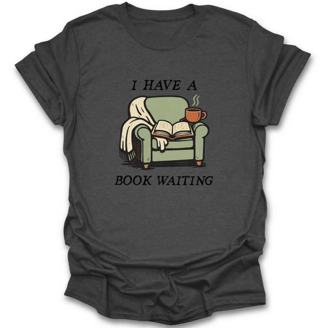 Dark gray t-shirt with a graphic of a green armchair, book, and cup of coffee with text 'I HAVE A BOOK WAITING' on a white background. funny book reading literary t shirt