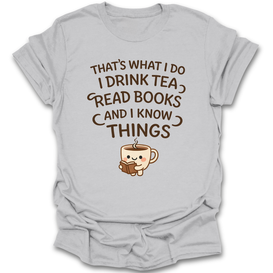Gray t-shirt with a graphic of a teacup reading a book and text 'That's what I do, I drink tea, read books, and I know things' on a white background. funny book reading literary t shirt
