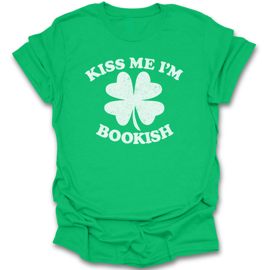 Green t-shirt with white four-leaf clover graphic and text 'Kiss Me I'm Bookish' on a white background st patricks day funny book reading literary t shirt