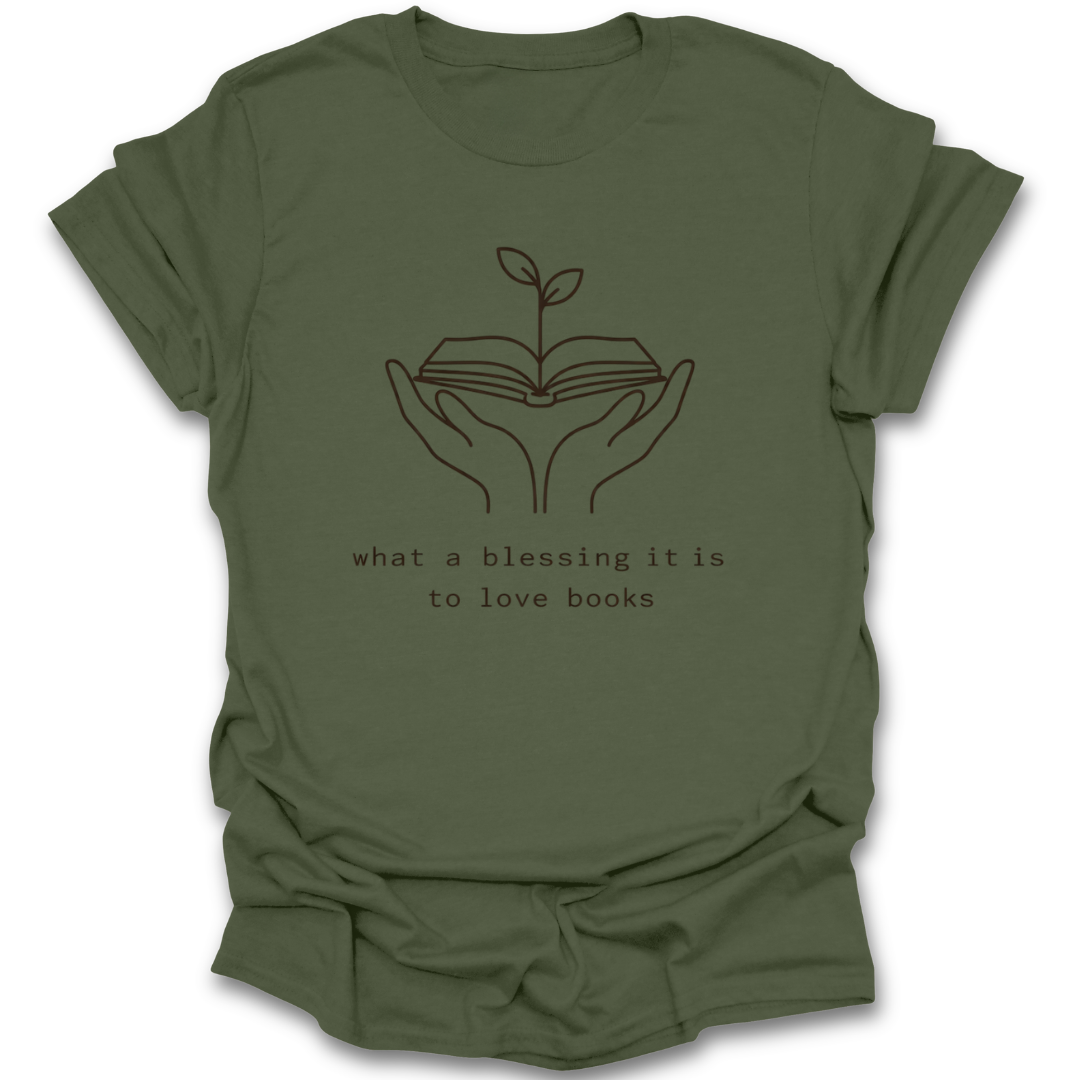 Green t-shirt with a graphic of hands holding an open book with a plant growing out of it and text 'what a blessing it is to love books' on a white background. quote book reading literary t shirt