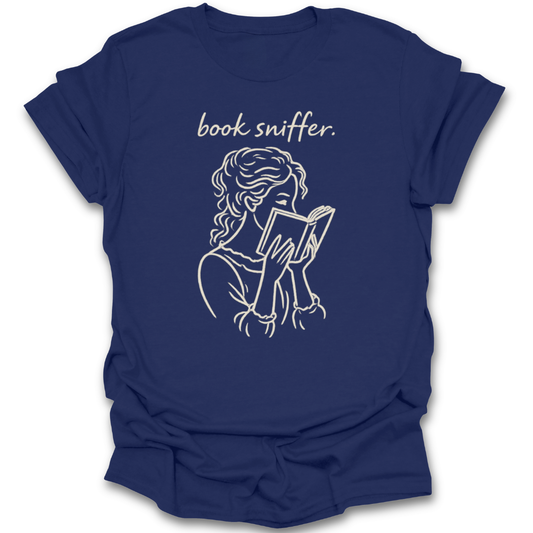 Navy blue t-shirt with a graphic of a person reading a book and the text 'book sniffer' on a white background. funny book reading literary t shirt
