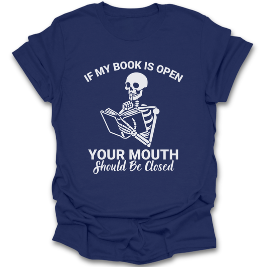 Navy blue t-shirt with a skeleton reading a book graphic and text on a white background funny book reading literary t shirt