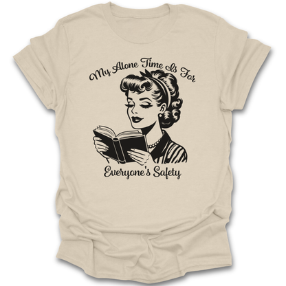 Beige t-shirt with a graphic of a woman reading a book and text 'My Alone Time Is For Everyone's Safety' on a white background. funny book reading literary t shirt