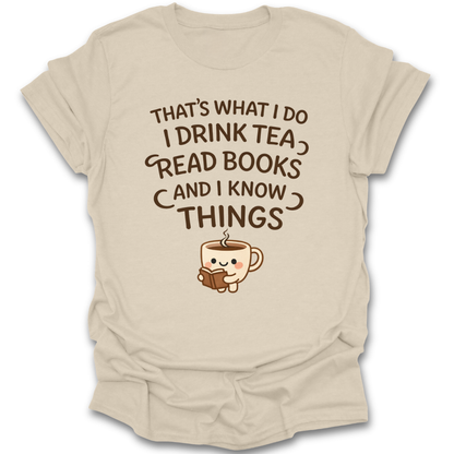 Beige t-shirt with a graphic of a teacup and text 'That's what I do, I drink tea, read books, and I know things' on a white background. funny book reading literary t shirt