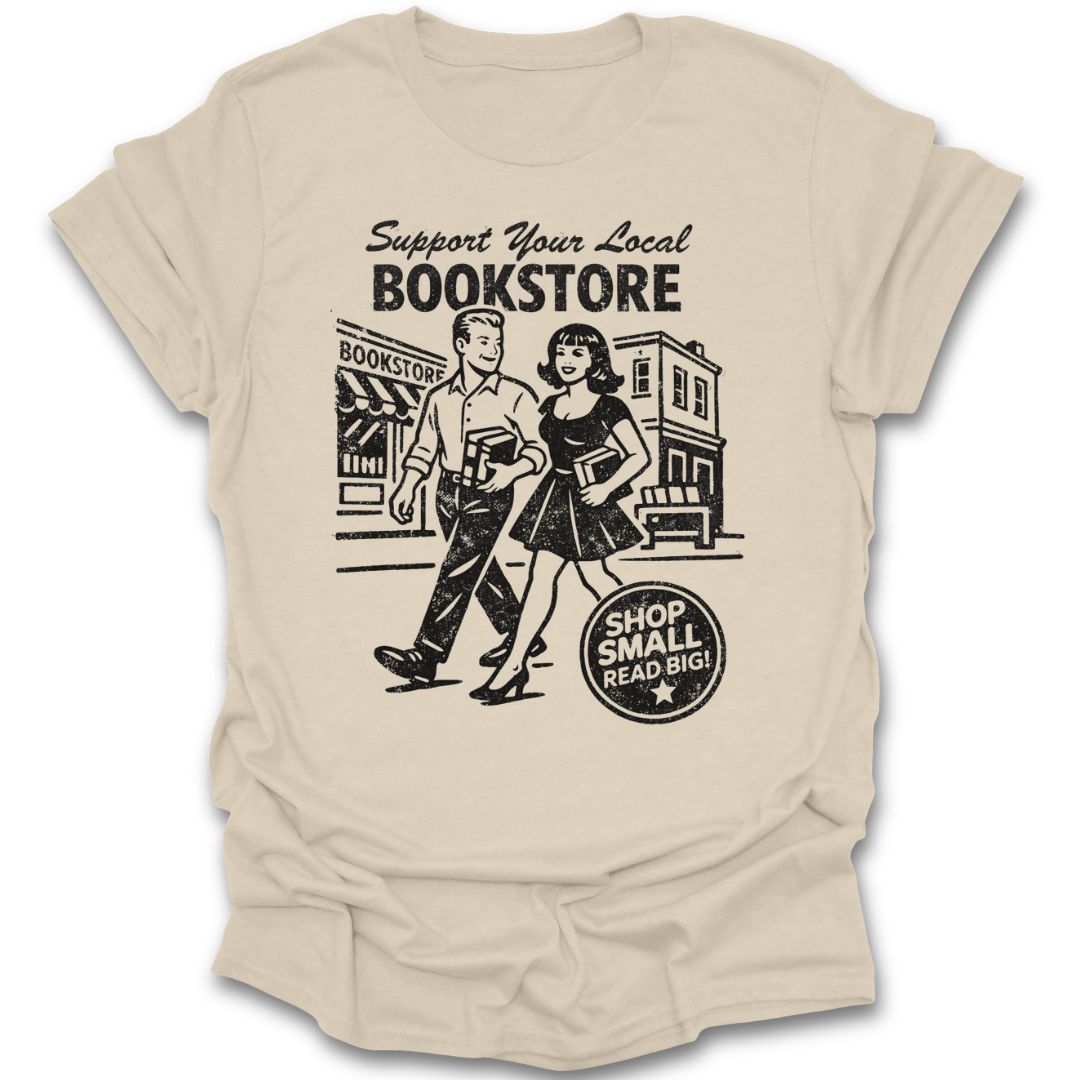 Beige t-shirt with a graphic of a man and woman walking past a bookstore and text 'Support Your Local Bookstore'. funny book reading literary t shirt
