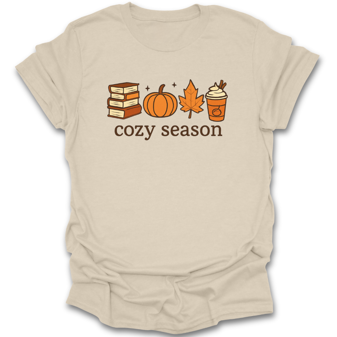 Beige t-shirt with autumn-themed graphics and 'cozy season' text on a white background book lover tee t shirt