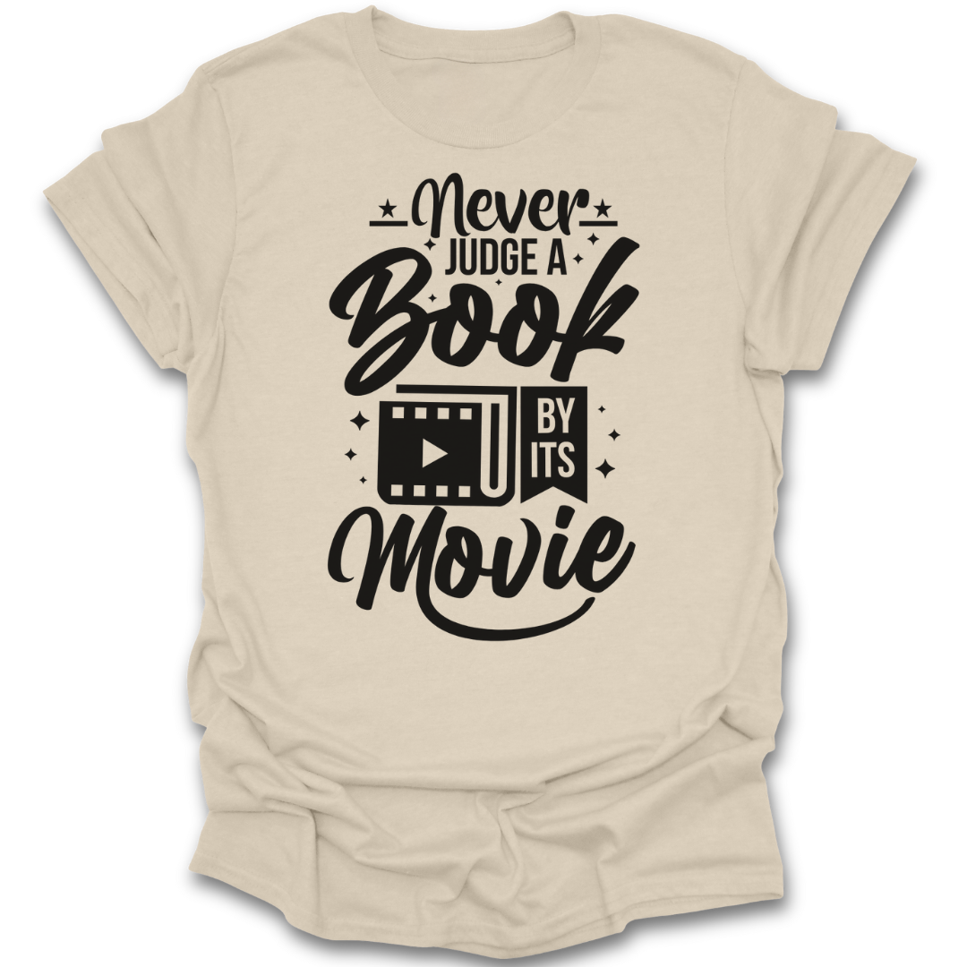 Beige t-shirt with black text 'Never Judge a Book by Its Movie' on a white background reaning t shirt