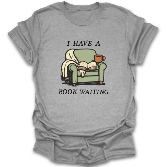 Gray t-shirt with a graphic of a green armchair, book, and cup with text 'I HAVE A BOOK WAITING' on a white background. funny book reading literary t shirt