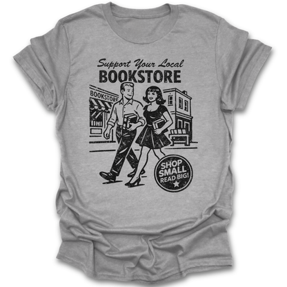 Gray t-shirt with 'Support Your Local Bookstore' graphic and text on a white background funny book reading literary t shirt