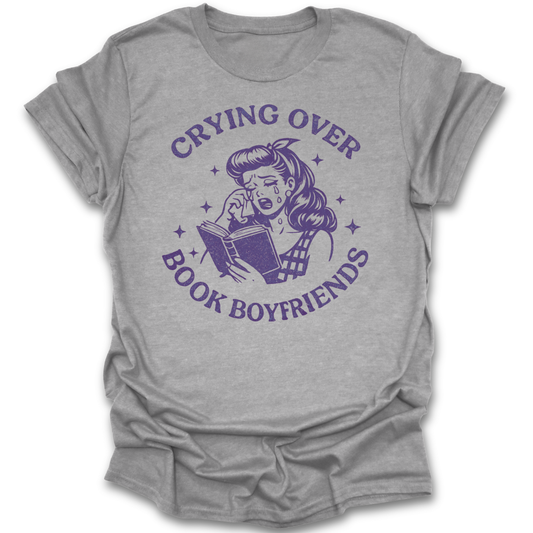 Gray t-shirt with purple graphic and text 'Crying over book boyfriends' on a white background romance funny book reading literary t shirt